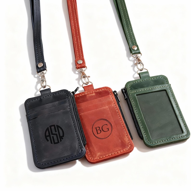 May include: Three leather ID badge holders in black, red, and green, each with a matching lanyard. The black holder has the initials "ASP" in a circle, the red has "BG", and the green has a clear window. All have a zipper and silver hardware.