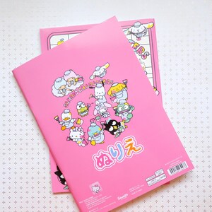 May include: Pink notebook with a Sanrio character design. The cover features a group of Sanrio characters holding paintbrushes and paint cans. The text "Sanrio Characters" and "ぬりえ" are printed on the cover.