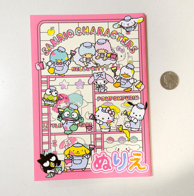 May include: A pink notebook with a colorful illustration of Sanrio characters painting. The characters include Hello Kitty, Pompompurin, Little Twin Stars, and others. The notebook has the text "Sanrio Characters" and "メルヘン" in Japanese.