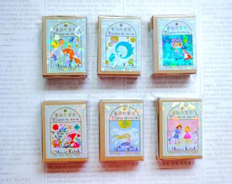 May include: Six small, colorful boxes with a holographic finish. Each box features a different illustration of a fairy tale scene. The boxes are labeled "童話の宝石 きらきらフレークシール" which translates to "Fairy Tale Jewels Sparkling Flake Stickers".