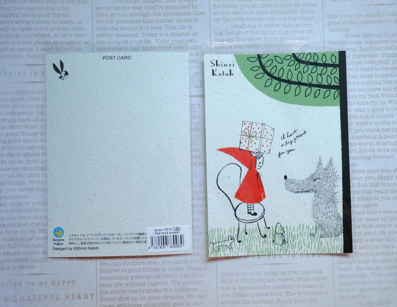 May include: A postcard featuring a red-hooded girl carrying a wrapped gift, a gray wolf, and a green tree. The text on the postcard reads "I have a big present for you".