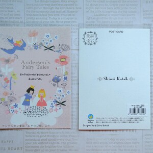 May include: A pink and white postcard with a whimsical illustration of a girl and a boy in front of a cloud with flowers and butterflies. The text on the postcard reads "Andersen's Fairy Tales" and "女の子はおやゆび半分の大きさし ありませんでした。" in Japanese. The back of the postcard has a floral design and the text "Shinzi Katoh" in black.