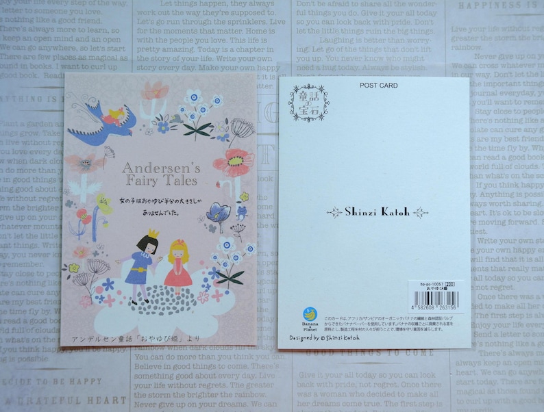 May include: A pink and white postcard with a whimsical illustration of a girl and a boy in front of a cloud with flowers and butterflies. The text on the postcard reads "Andersen's Fairy Tales" and "女の子はおやゆび半分の大きさし ありませんでした。" in Japanese. The back of the postcard has a floral design and the text "Shinzi Katoh" in black.