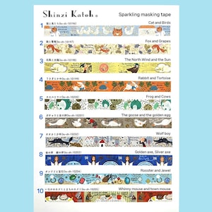 May include: A sheet of sparkling masking tape featuring ten different designs. Each design has a unique theme, including cats and birds, foxes and grapes, and the North Wind and the Sun. The tape is labeled "Shinzi Katoh."