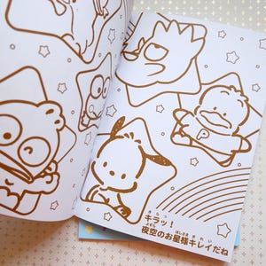 May include: A coloring book with a white background and brown outlines of various characters. The characters include a fish, a star, a duck, and a dog. The text on the page reads "キラッ! 夜空のお星様キレイだね".