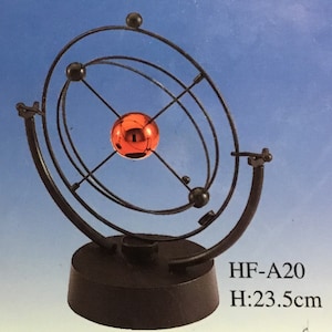 Puede incluir: Una escultura de escritorio de metal negro con una esfera naranja central y anillos orbitales. La base es redonda y la altura es de 23,5 cm. El texto "HF-A20" es visible.