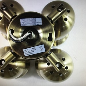 May include: Five antique brass-effect light fittings. Each fitting features a circular base with mounting holes and a spherical shade. The fixtures have a vintage aesthetic, suitable for home lighting. The label reads "LIGHT KIT" and "MADE IN TAIWAN".