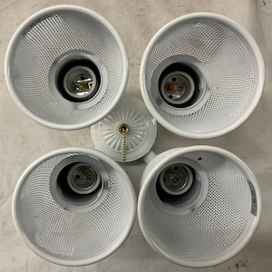 May include: A white, four-light ceiling fan fixture with mesh shades. The fixture has a central base with a decorative design and a pull chain. Each light socket is visible within the mesh shade.