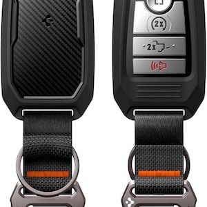 Puede incluir: Dos llaveros de coche negros con un dise&ntilde;o de fibra de carbono y un mosquet&oacute;n de metal. Uno tiene botones para bloquear y desbloquear, y el otro tiene un panel en blanco de fibra de carbono. Ambos tienen una correa negra con una raya naranja.
