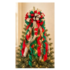 May include: A decorative Christmas tree topper bow featuring multiple loops and long, cascading ribbons in solid red, deep green, and natural tan burlap. The bow is constructed from wired fabric ribbons arranged in a full, symmetrical cluster.
