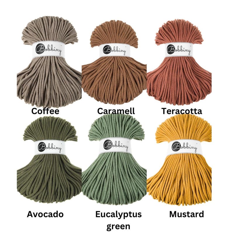 May include: Six skeins of Bobbiny cotton cord arranged in two rows. The colors are coffee, caramell, teracotta, avocado, eucalyptus green, and mustard. Each skein is secured with a white paper band featuring the Bobbiny logo in black text.