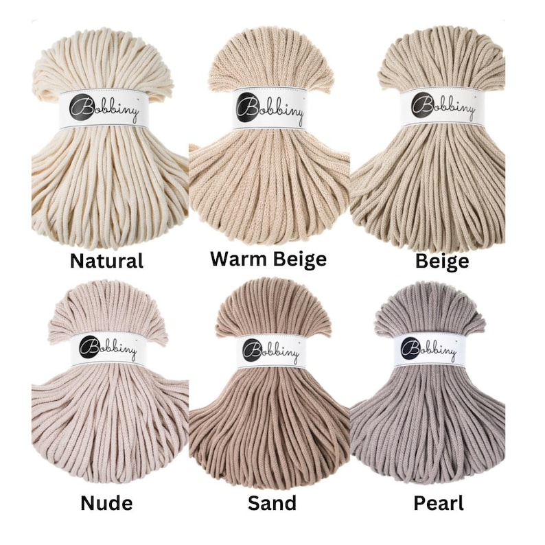 May include: Six skeins of Bobbiny cotton cord arranged in two rows. Each skein is secured with a white paper band featuring the Bobbiny logo. The colors displayed are labeled as Natural, Warm Beige, Beige, Nude, Sand, and Pearl, showing various neutral shades of off-white, tan, brown, and light gray.