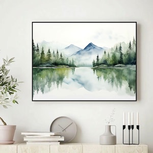 May include: A watercolor painting of a mountain lake scene with a reflection of the trees and mountains in the water. The painting is framed in a black frame.