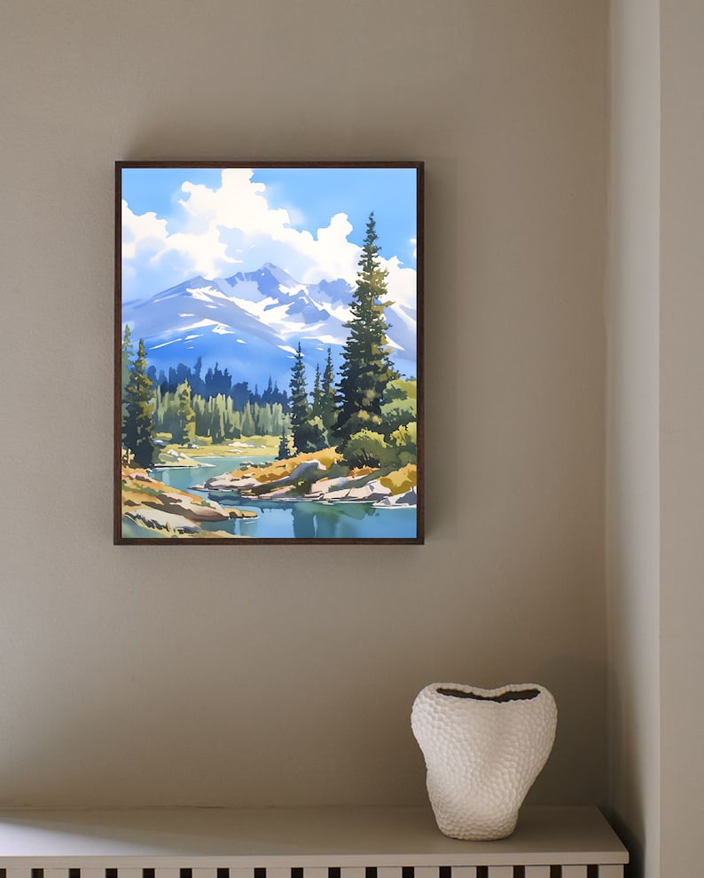May include: A framed painting of a mountain lake scene with a blue sky, white clouds, and green trees. The lake is surrounded by rocks and the mountains are in the background.