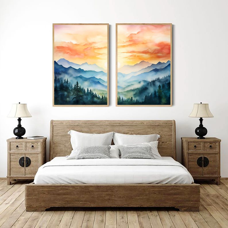 May include: Two framed watercolor landscape paintings depict a mountain range and forest in shades of blue and green, under a vibrant orange and yellow sky. The artwork hangs above a wooden bed with white bedding, flanked by matching nightstands and lamps.