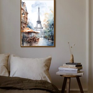 K&ouml;nnte beinhalten: Ein Aquarellbild des Eiffelturms in Paris, Frankreich. Das Bild zeigt eine Stra&szlig;enszene mit einem Caf&eacute; und Passanten. Das Bild ist in einem Holzrahmen gerahmt.