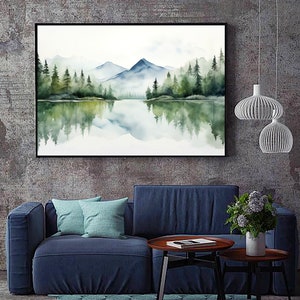 May include: A watercolor painting of a mountain lake scene with a reflection of the trees and mountains in the water. The painting is framed in black and hanging on a gray wall.