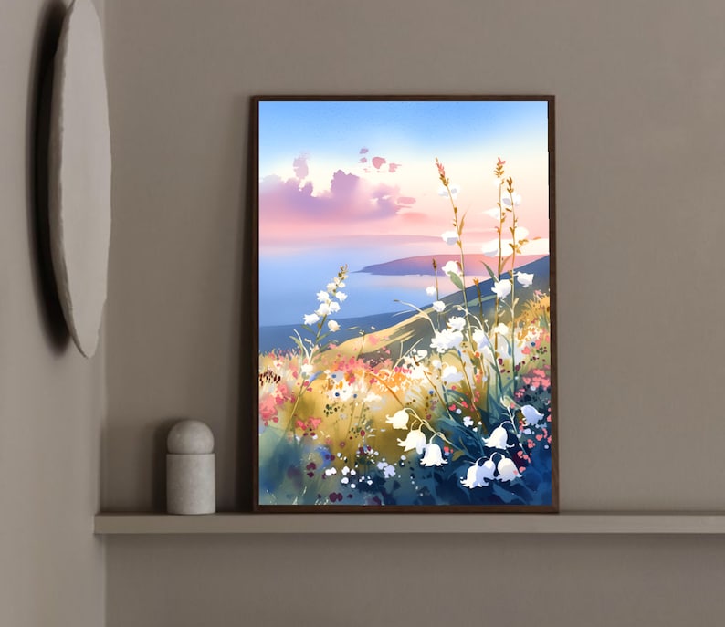 Pode incluir: Uma pintura em aquarela emoldurada retrata uma paisagem serena. Flores brancas em forma de sino florescem em primeiro plano, com uma colina e um corpo de &aacute;gua ao fundo. O c&eacute;u transita do azul para o rosa, sugerindo um p&ocirc;r do sol.