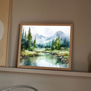 May include: Watercolor painting of a mountain landscape with a river flowing through it. The painting features a lush green forest with tall trees and a blue sky with white clouds. The mountains are in the background and are covered in a light blue haze.