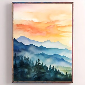 May include: Watercolor painting of a mountain landscape with a sunset. The artwork features layers of blue mountains, a forest of dark green trees, and a vibrant orange and yellow sky. The painting is framed in a rustic wooden frame.