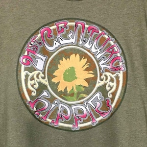 May include: A green t-shirt with a vintage-style graphic of a sunflower in a circle with the text "21st Century Hippie".