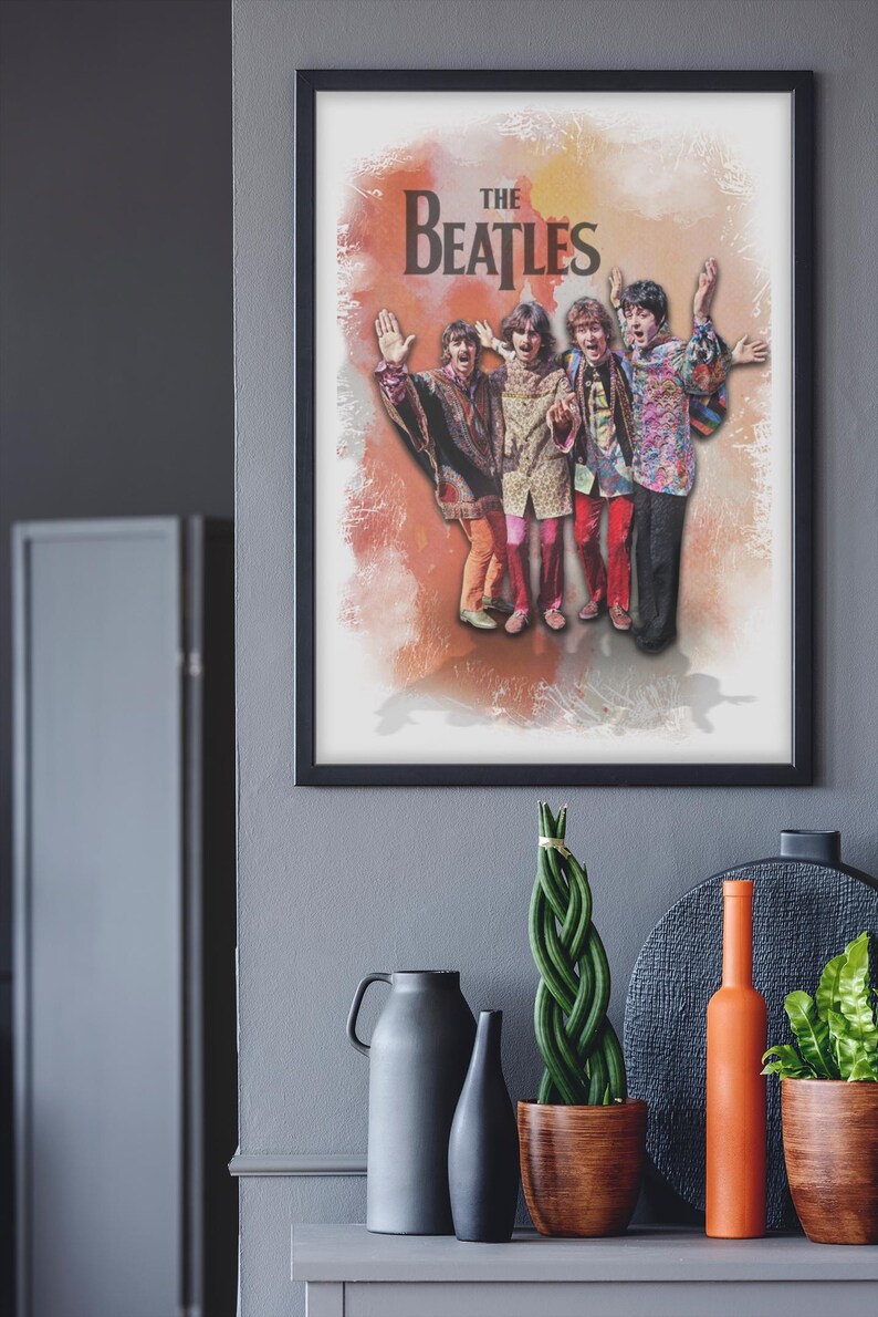 K&ouml;nnte beinhalten: Ein gerahmter Wandkunstdruck mit einer Illustration der Beatles im Aquarellstil. Die vier Bandmitglieder sind in farbenfroher, gemusterter Kleidung mit erhobenen Armen vor einem weichen, orange-wei&szlig;en, texturierten Hintergrund dargestellt.
