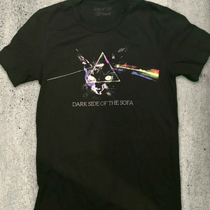 May include: Black t-shirt with a graphic of a cat's face in a triangle with a rainbow beam of light. The text "Dark Side of the Sofa" is printed below the graphic.