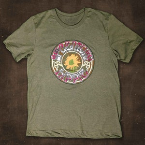 May include: A green t-shirt with a vintage-style graphic of a sunflower and the words "Peace Loving Hippie".