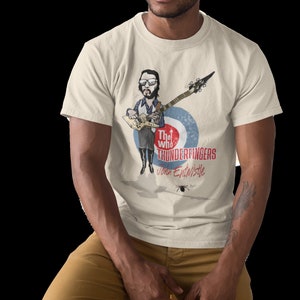 May include: A white t-shirt with a cartoon illustration of a man playing a guitar. The text "The Who Thunderfingers John Entwistle" is printed on the shirt.