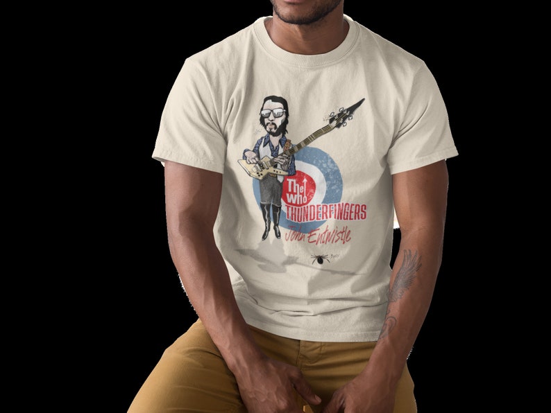 May include: A white t-shirt with a cartoon illustration of a man playing a guitar. The text "The Who Thunderfingers John Entwistle" is printed on the shirt.