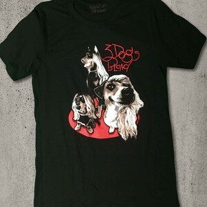 May include: Black t-shirt with a red graphic of three dogs with long hair. The text "3 Dogs Blond" is written in red above the dogs.