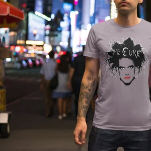 May include: A gray t-shirt with a black and white image of Robert Smith, the lead singer of The Cure, with the band's name printed above his head.
