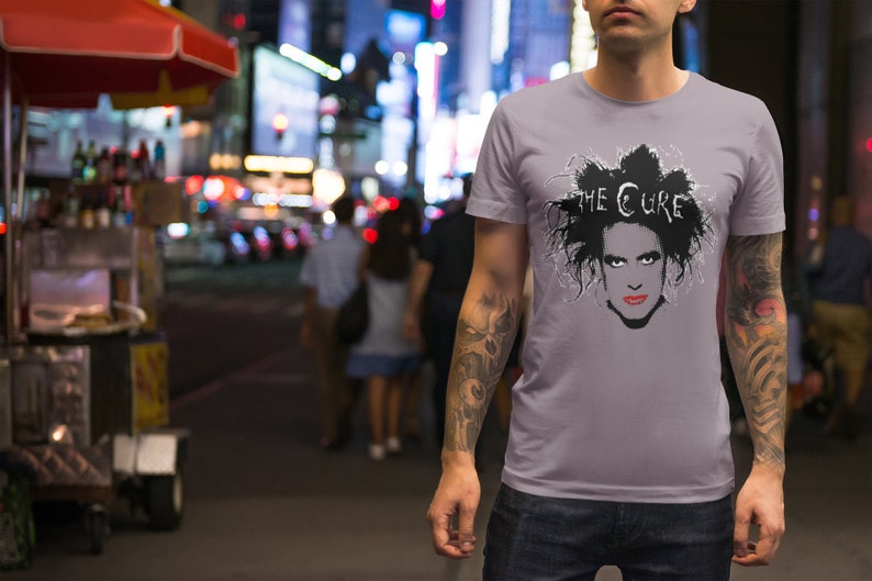 May include: A gray t-shirt with a black and white image of Robert Smith, the lead singer of The Cure, with the band's name printed above his head.