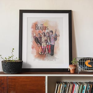 K&ouml;nnte beinhalten: Ein gerahmter Kunstdruck mit einer Illustration im Aquarellstil der Band The Beatles. Die vier Mitglieder sind zusammen in bunter Kleidung vor einem weichen, orange- und braunfarbenen Hintergrund mit dem Schriftzug The Beatles abgebildet.