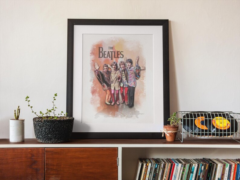 K&ouml;nnte beinhalten: Ein gerahmter Kunstdruck mit einer Illustration im Aquarellstil der Band The Beatles. Die vier Mitglieder sind zusammen in bunter Kleidung vor einem weichen, orange- und braunfarbenen Hintergrund mit dem Schriftzug The Beatles abgebildet.