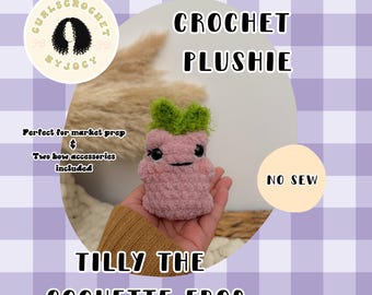 May include: A handmade crochet plushie of Tilly the Coquette Frog. The pink frog has green leafy hair and black eyes. The text "CROCHET PLUSHIE" and "TILLY THE COQUETTE FROG" are displayed. The image also includes the text "NO SEW".