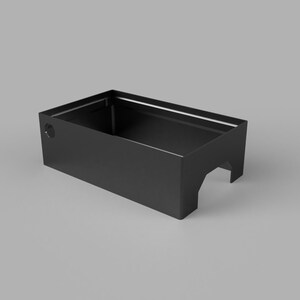 May include: A black rectangular container with a cutout on one side and a circular hole. The container is made of a solid material and has a matte finish. The object is set against a gray background.