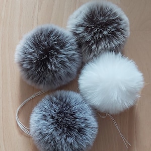 Op de afbeelding: Vier pluche pompoenen in verschillende tinten grijs en wit. De pompoenen zijn gemaakt van zacht, pluche bont en zijn perfect om een ​​toets van whimsy toe te voegen aan elk project.