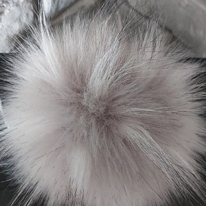 May include: A fluffy grey pom pom made of faux fur. The pom pom is about 10 inches in diameter. Grey 2.