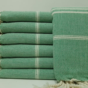 May include: A stack of six green and white striped towels with fringe edges. The towels are made of a soft, absorbent material.