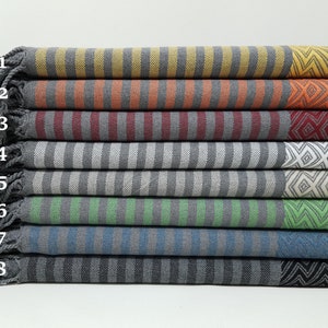 May include: A stack of eight striped towels with fringed edges. The towels are in various colors, including yellow, orange, red, gray, white, green, blue, and black.