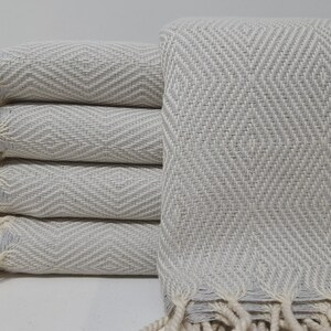 May include: A stack of five off-white cotton towels with a herringbone pattern and fringe edges.