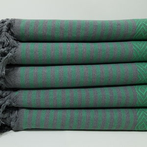 May include: A stack of five green and gray striped towels with fringe edges. The towels have a geometric pattern on one side.