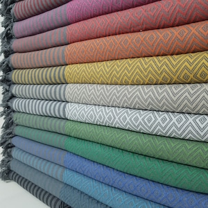 May include: A stack of colorful striped and patterned towels. The towels are folded and stacked on top of each other. The towels are made of a soft, absorbent material.