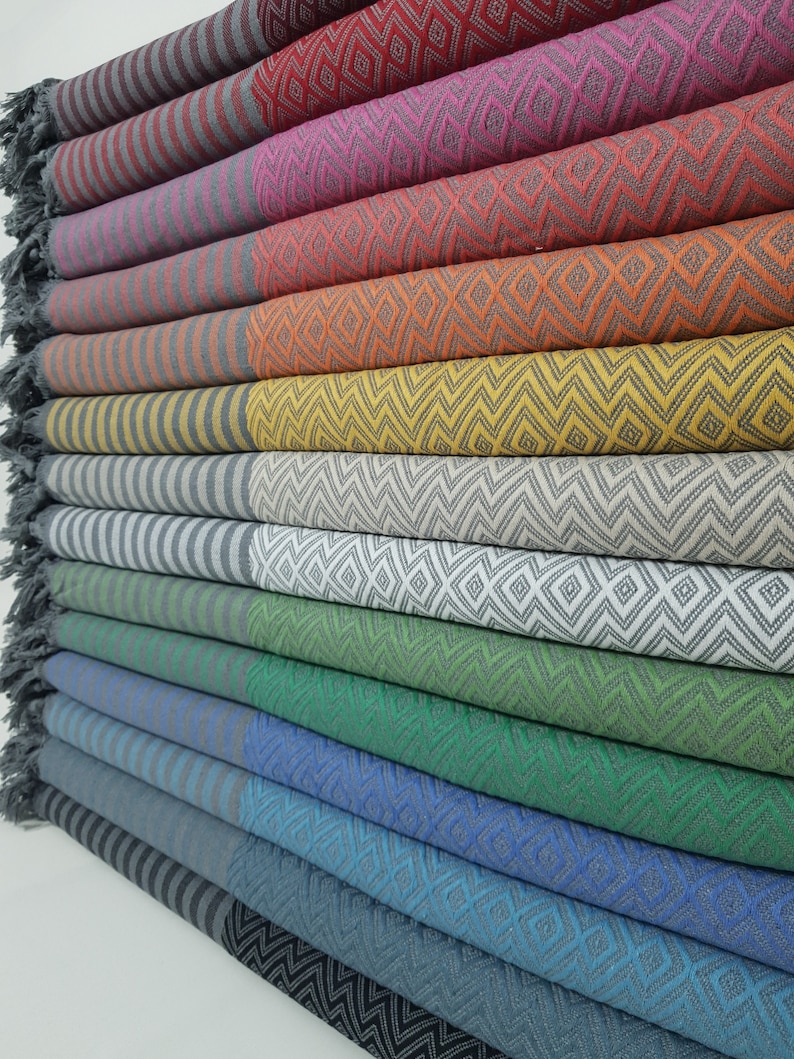 May include: A stack of colorful striped and patterned towels. The towels are folded and stacked on top of each other. The towels are made of a soft, absorbent material.