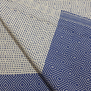 K&ouml;nnte beinhalten: Eine wei&szlig;e und blaue gewebte Decke mit einem Rautenmuster. Die Decke ist aus einem weichen, gewebten Stoff.