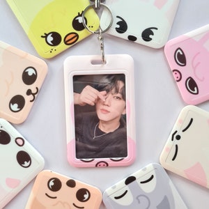 Könnte beinhalten: Ein rosa-weißer Ausweishalter mit einem durchsichtigen Plastikfenster für ein Foto. Der Halter hat verschiedene Comic-Tiermotive, darunter ein Küken, ein Kaninchen, ein Schwein, eine Katze und ein Hund. Der Halter ist an einem weißen Lanyard befestigt.