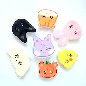 Peut inclure: Ensemble de sept épingles de personnages de dessins animés d'animaux colorés. Les épingles représentent un chat noir, un poussin jaune, un chat violet, un chien blanc, un ours orange, un lapin rose et un personnage orange et blanc avec un chignon.