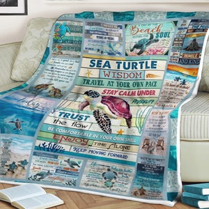 May include: A blue and white throw blanket with a sea turtle design and inspirational quotes. The blanket features a sea turtle with the words "Sea Turtle Wisdom" and "Travel at your own pace, Stay calm under pressure".