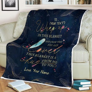May include: A navy blue fleece blanket with a white border and a gold and white design of whales and stars. The text "To... (Your Text) Wrap up in this blanket and know that you are loved. This blanket is a hug from me to you. Love, Your Name" is printed on the blanket.